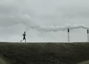 Man running in front of coal plant