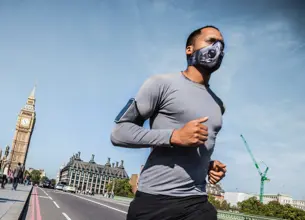 Man running across Westminster Bridge with mask on